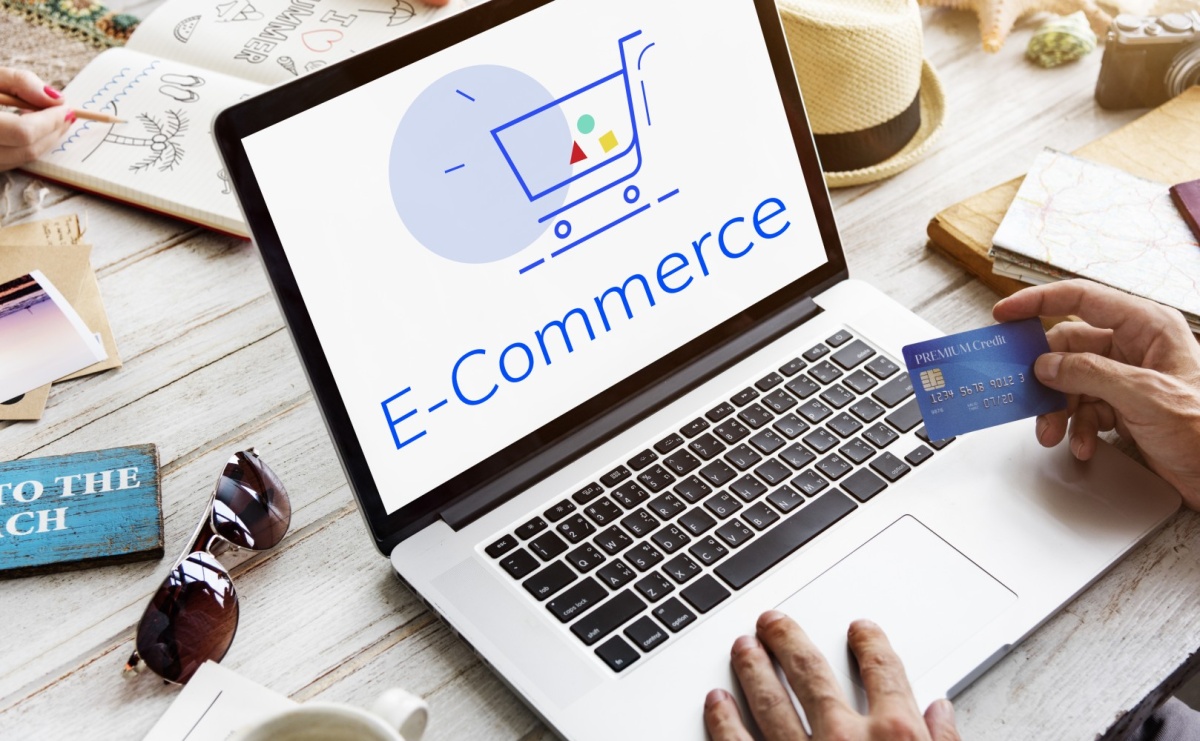 Agencja PrestaShop – profesjonalne rozwiązania e-commerce, laptop z grafiką koszyka internetowego i napisem E-Commerce.