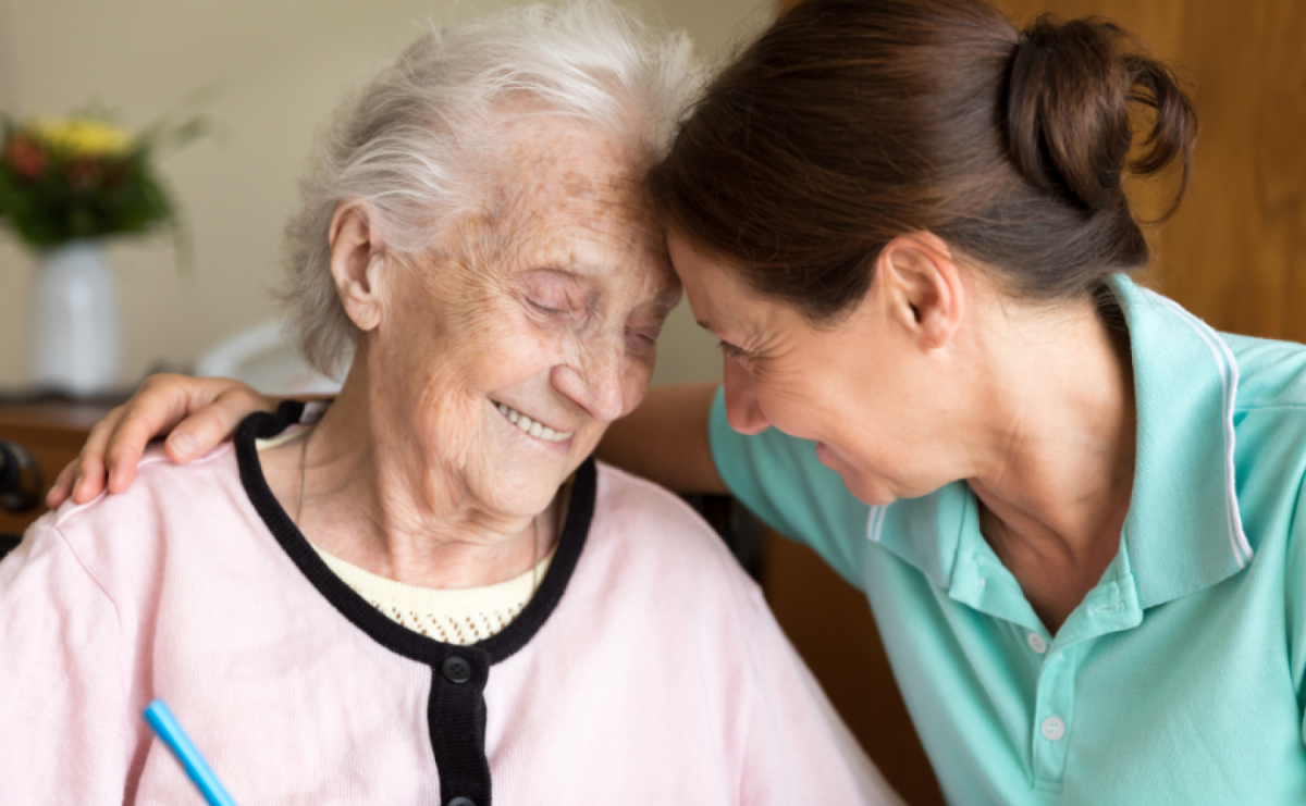 opiekunka seniorki przytula się do uśmiechniętej podopiecznej - szukasz opiekunki dla swojej mamy - znajdziesz ją przez dodanie ogłoszenia za darmo w zleceniadlaopiekunek.pl